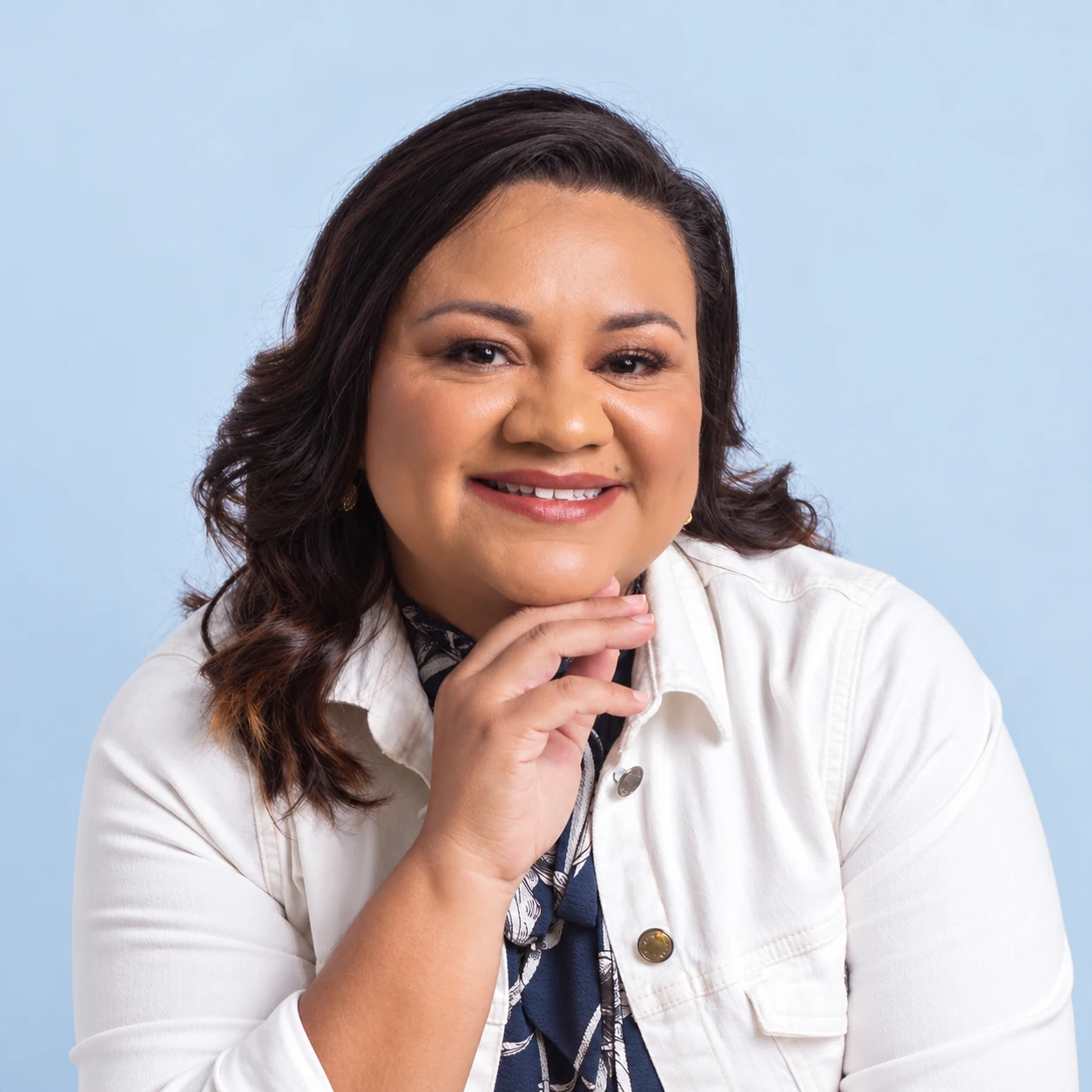 Joceline Barreto sorrindo, com roupa clara e a mão próxima ao rosto